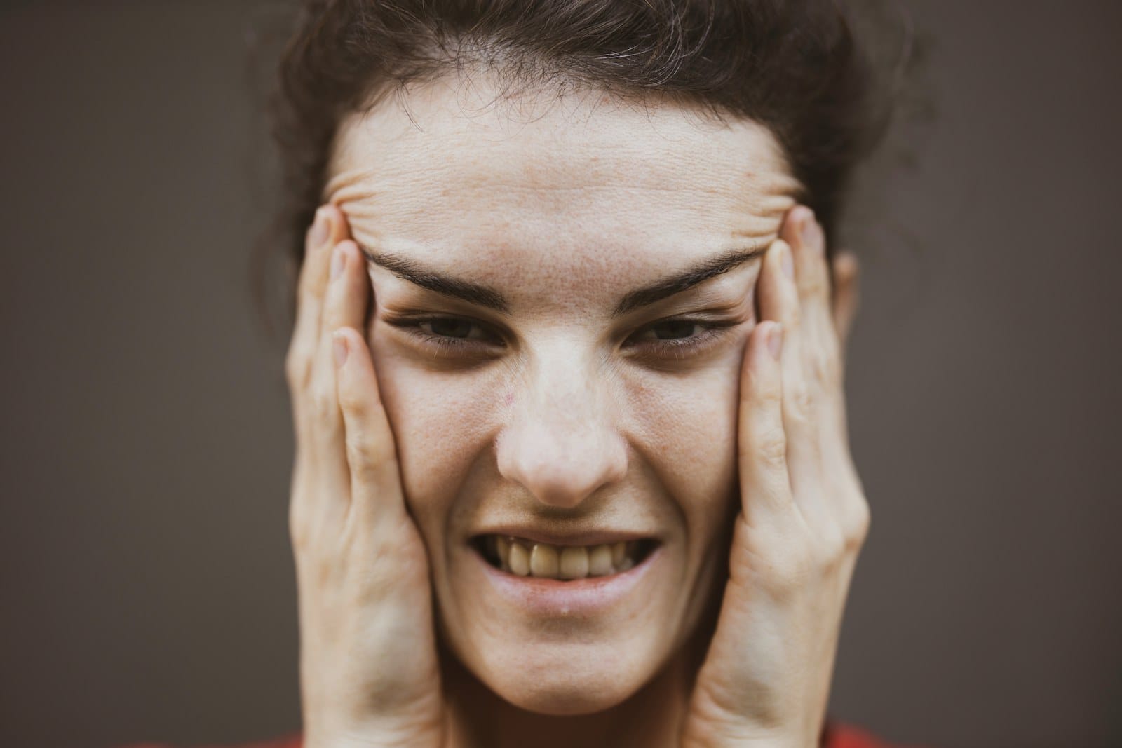 femme qui pose la main sur sa mâchoire, gênée par une douleur